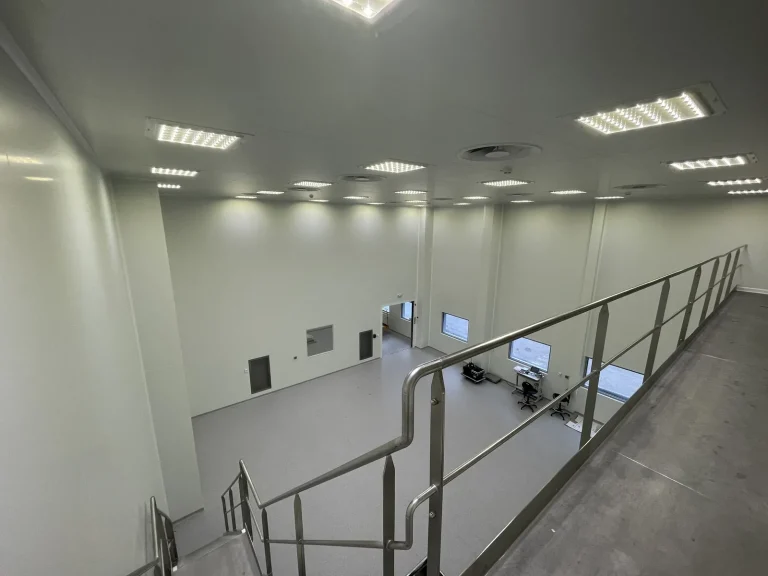 Passerelle technique en acier surplombant une salle blanche rénovée